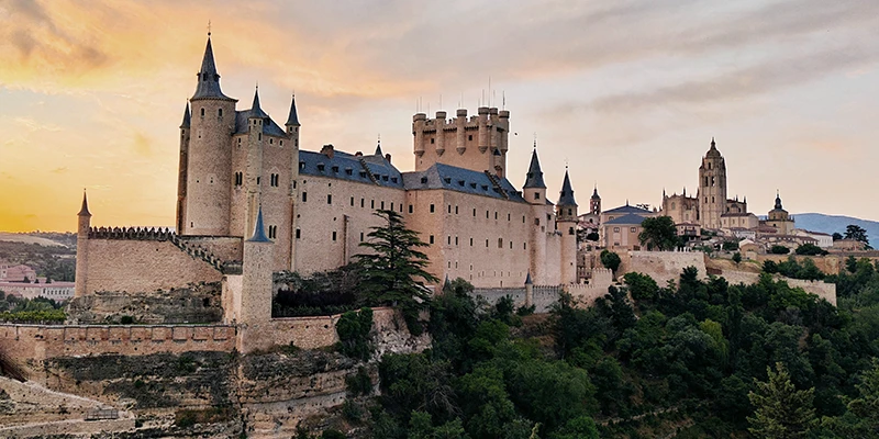 The Alcázar of Segovia perched dramatically on a rocky promontory where two river valleys converge